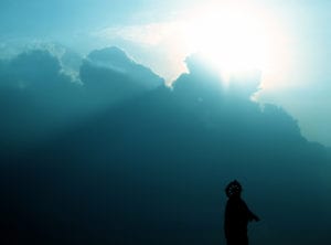 Sun rising over blue sky, holy man walking