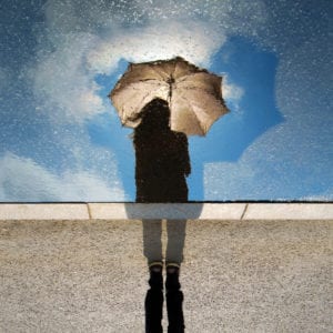 Woman with umbrella standing in sunshine and rain