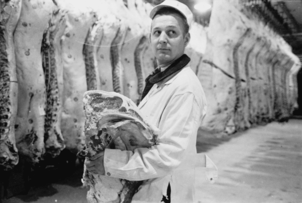 A photograph by Stanley Kubrick showing a butcher holding a slab of beef