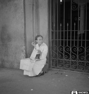 Woman crouched down on the street waiting to sell lottery tickets to passerbys.