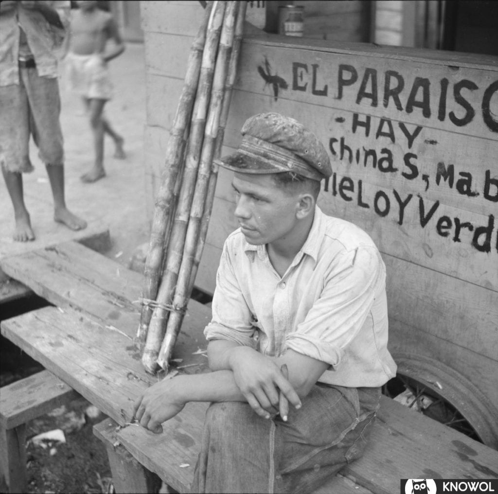 Longshoreman sitting on a bench while smoking a cigar.